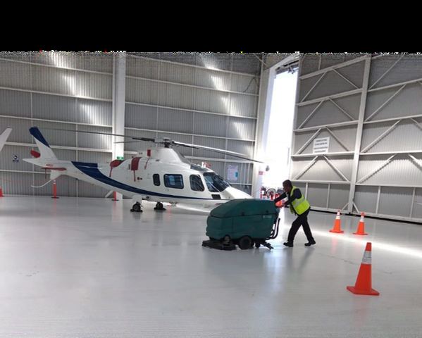 Personal de ANMIX operando una fregadora industrial en un hangar